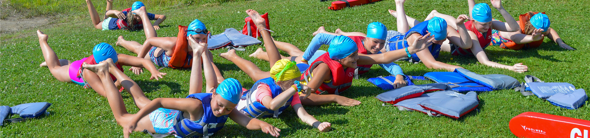  A group of girls in bathing suits and swim caps practice swimming on land 