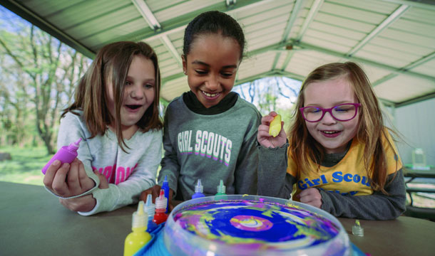 Girl Scouts smiling down at board game
