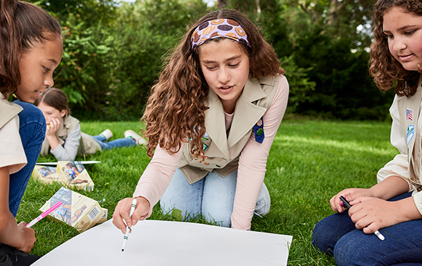 Girl Scouts making a poster outside