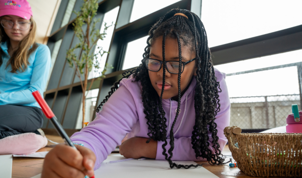 adult volunteer and girl scout sitting at table looking on phone at digital resources