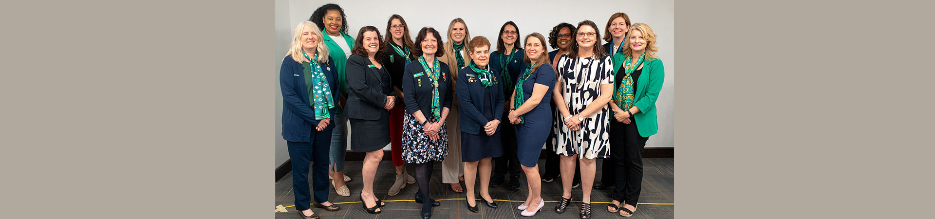  A diverse group of 13 women wearing different combinations of navy blue, white, and green 