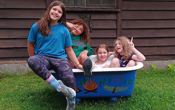 Four young girls playing in a hand-painted tub on a lawn