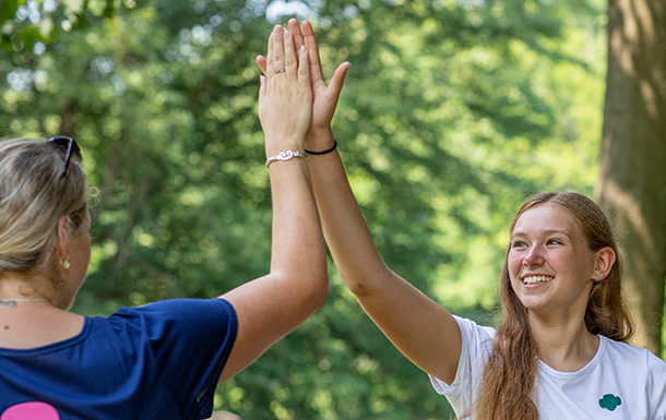 A teen girl and an adult woman high fiving outdoors