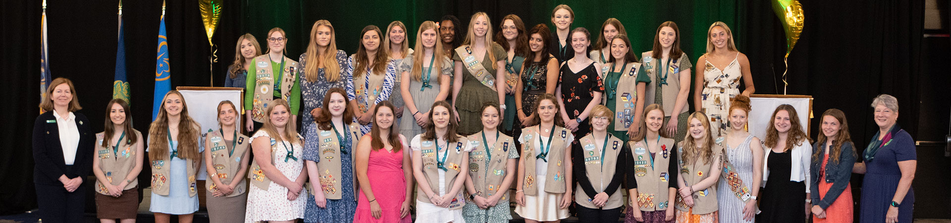  A group of Girl Scouts standing on a stage and smiling for the camera 
