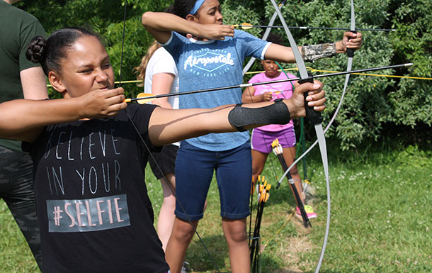 A group of girls drawing their bows at archery practice